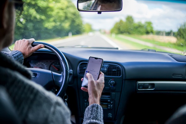 A man use smartphone while driving in the car.