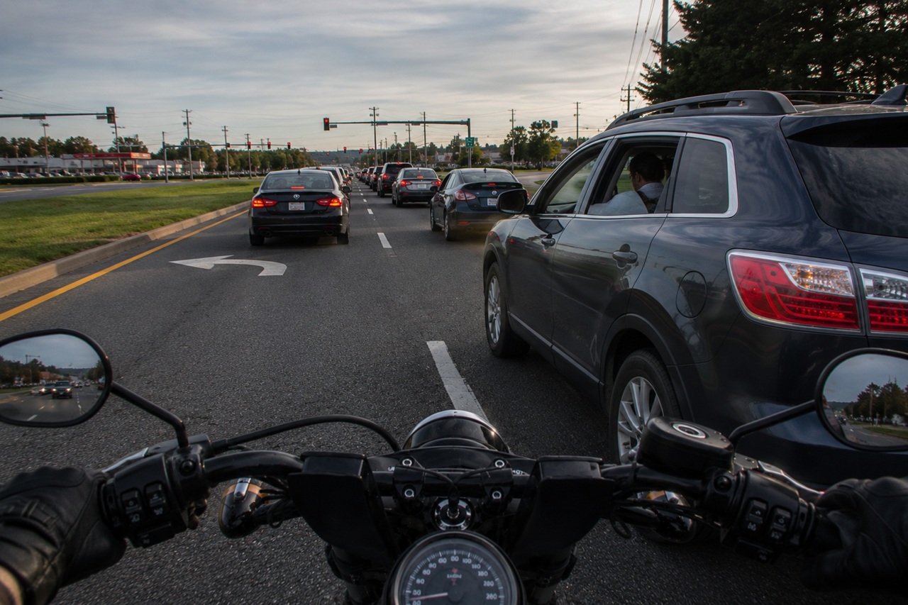 A first-person perspective of a motorcyclist navigating heavy, multi-lane traffic during the day, showing the rider positioned between lines of cars and SUVs. This viewpoint highlights common hazards such as vehicle proximity and traffic congestion that contribute to motorcycle crash risks in Delaware.